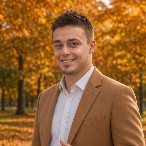 Kevin smiling in a park full of autumn leaves